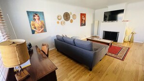 A living room with a sofa, a TV, a fireplace, and decorative wall art. - Gorgeous, private, comfy, clean & close to EDO (Albuquerque)