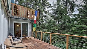 A wooden deck with wicker furniture and a glass door leading to an interior space.