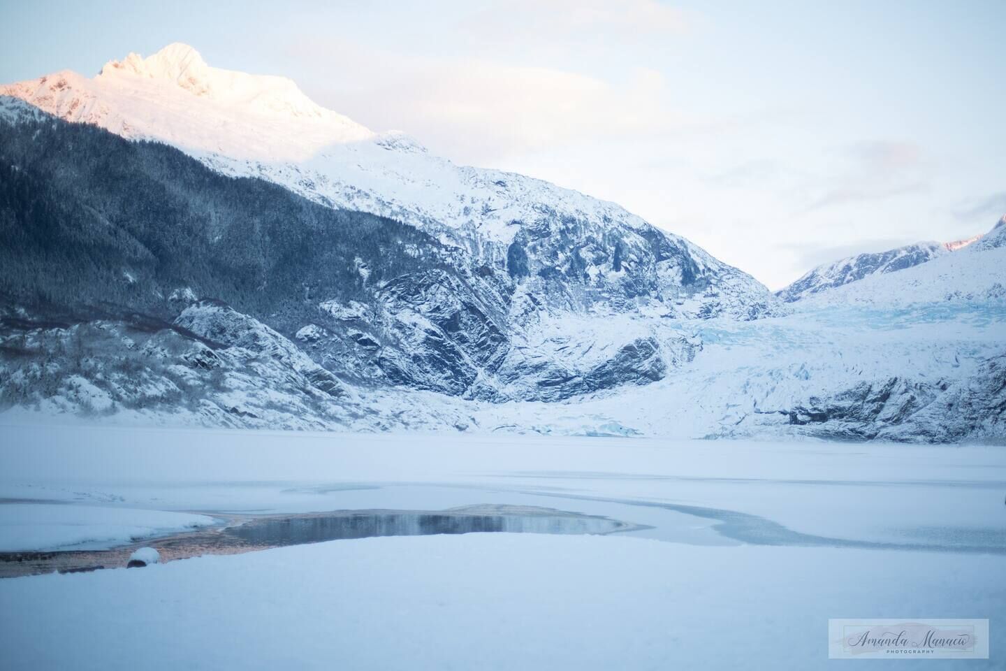 Un paisaje montañoso cubierto de nieve con un lago congelado.