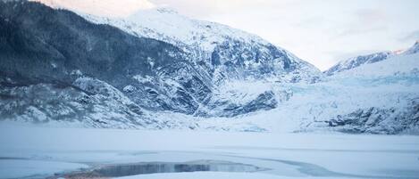 Un paisaje montañoso cubierto de nieve con un lago congelado.