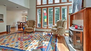 A spacious living room with a large window, a fireplace, and a patterned rug.