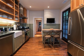 stainless still refrigerator and french doors that lead out to the side yard and the gas grill