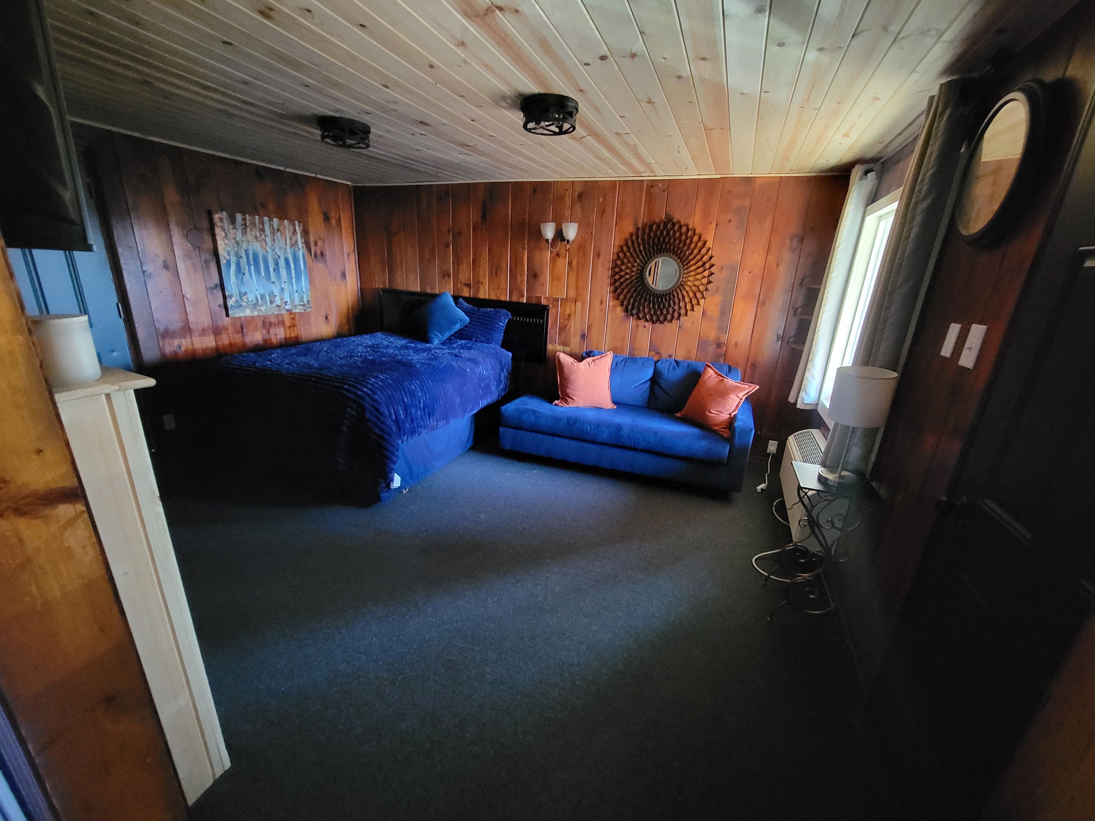A room with a bed, a sofa, and a wall-mounted mirror.