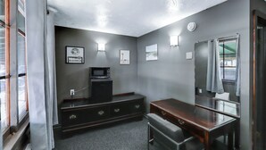 A compact bathroom with a dark wood vanity, a microwave, and framed artwork on the wall. - Cedar Village Motel (Spokane)