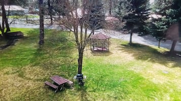 A park with a picnic table, a gazebo, and a tree.