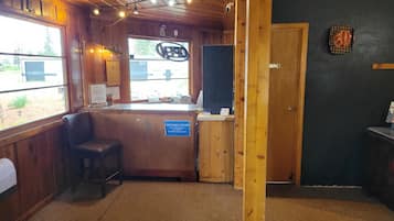 Interior de madera con mostrador de recepción, un cartel que indica las opciones de pago y una vista por la ventana.
