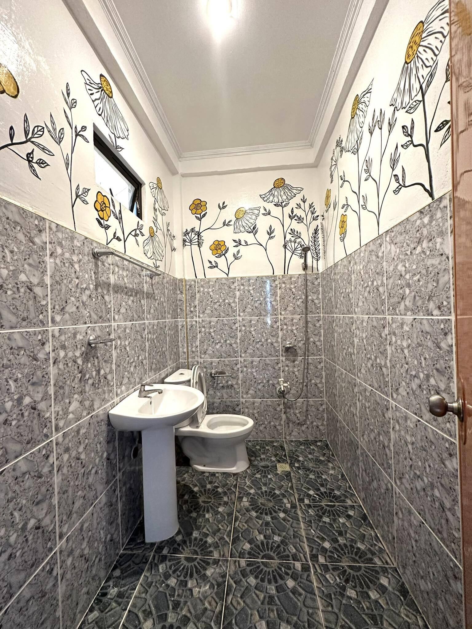 A bathroom with a sink, toilet, and shower. The walls have floral patterns, and the floor has a mosaic design.