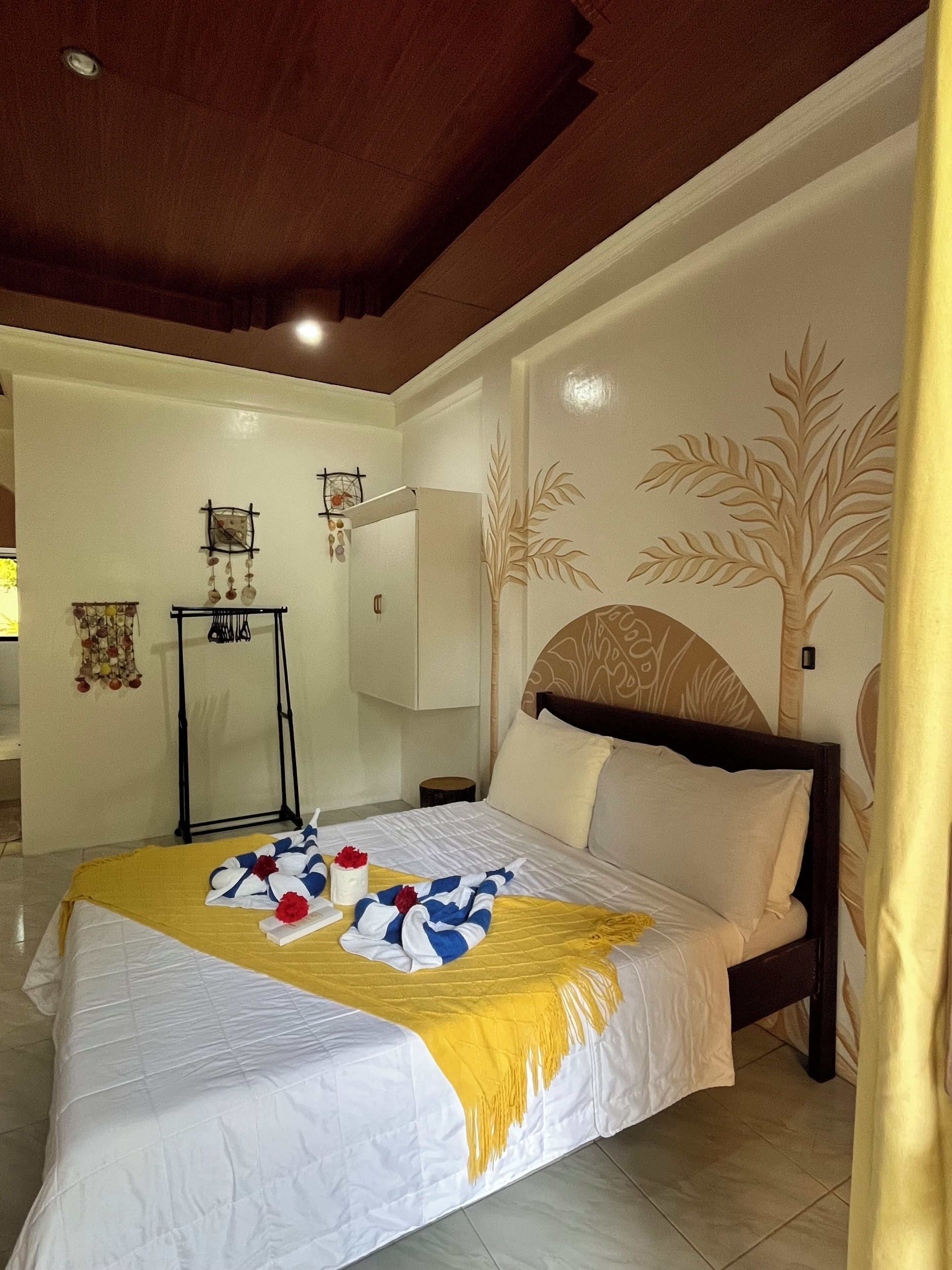 Una camera d'albergo con un letto, un comodino, una sveglia a muro e un pannello decorativo.