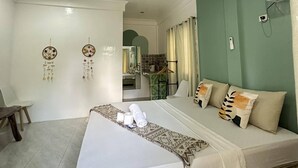 Una camera d'albergo con un letto grande, una scrivania piccola, una sedia, uno specchio e una parete verde decorativa.