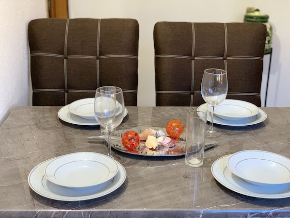 A dining table with four plates, two wine glasses, and a decorative glass bowl with seashells and a red ornament. - Turtle Condo at sun house whit pool (Lomas del Calvario)