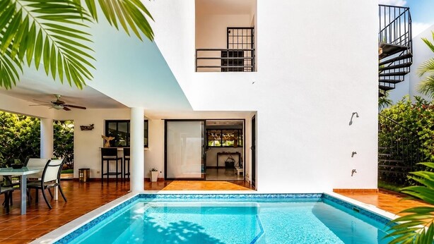 Une maison moderne dotée d’une piscine, d’un coin repas et d’un escalier.
