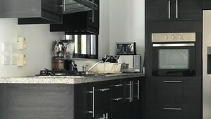 Une cuisine moderne avec des meubles de rangement sombres, un four encastré et une machine à café.