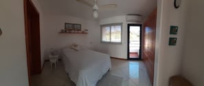 A bedroom with a bed, a nightstand, a ceiling fan, a window, and a door leading to a balcony. - 3-BR Gated Villa, Kitchen, Pool, Wi-Fi, AC (Las Terrenas)