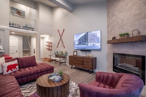 A modern living room with a fireplace, a television, and a staircase leading to an upper level.