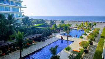 Un resort con piscina, palmeras y vista a la playa.