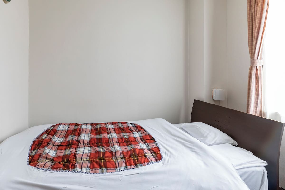 Ein Bett mit einer karierten Decke, weißen Laken und einem Kopfteil.