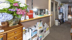 A reception desk with a vase of flowers, a paywall, and a calendar. - Tabist Hotel Yakumo Matsue (Matsue)