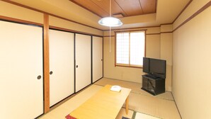 A traditional Japanese room with tatami flooring, sliding doors, a television, and a ceiling light. - Tabist Hotel Yakumo Matsue (Matsue)