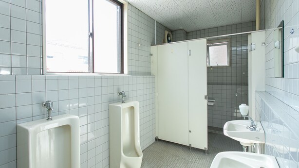 Des toilettes publiques équipées de deux urinoirs, d’un lavabo et d’un miroir.