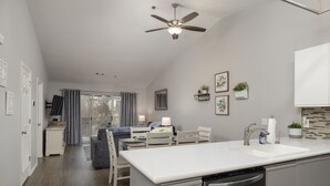 Une cuisine moderne avec un plan de travail blanc, un lave-vaisselle encastré et un ventilateur de plafond.