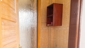 Une salle de bain avec une porte en bois, des toilettes et un meuble de rangement au-dessus.