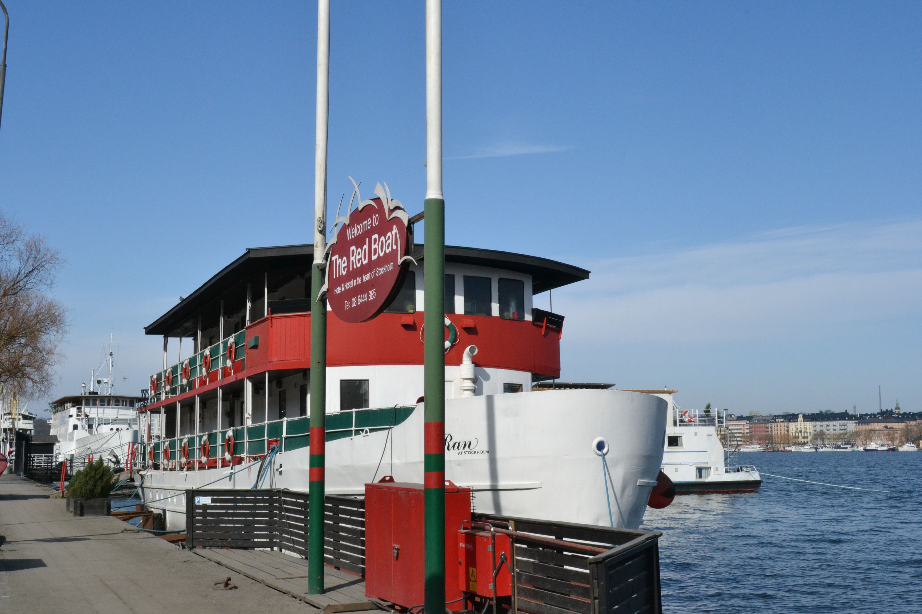 Un bateau rouge et blanc était amarré à un quai, et une pancarte indiquait : « Bienvenue à bord du Red Boat. »