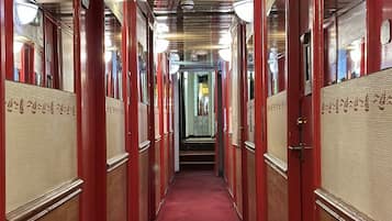 A corridor with red doors, a red carpet, and a ceiling with lights.