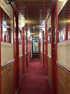 A corridor with red doors, a red carpet, and a ceiling with lights. - The Red Boat (Stockholm)