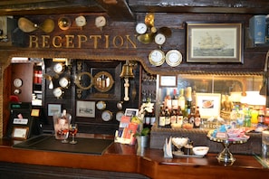A reception area with a wooden interior, clocks, and a framed map on the wall. - The Red Boat (Stockholm)