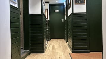 A hallway with wooden flooring, green walls, and a door at the end.