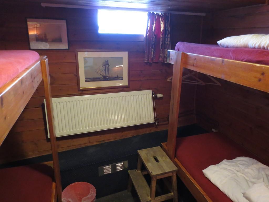 Habitación con literas, un cuadro en la pared, un radiador y un taburete de madera.