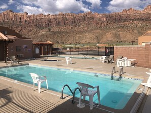 A pool area with lounge chairs and a view of a mountainous landscape. - Moab Behind the Rocks Retreat - 3B/2.5B- Garage/Pool (Moab)