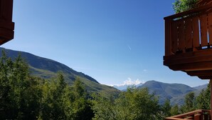 Udsigt over et bjerglandskab med en træterrasse og en betonmur i forgrunden.