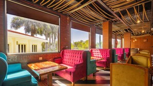 Un restaurante con asientos rojos y turquesas, ventanas amplias y techo de madera.