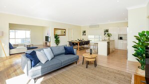 Ein modernes Wohnzimmer mit einer grauen Couch, einem Couchtisch und einem Essbereich mit Tisch und Stühlen.