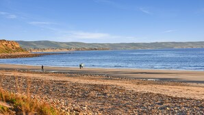 Ein Küstenstrand mit Kieselsteinen und freiem Blick auf das Meer.
