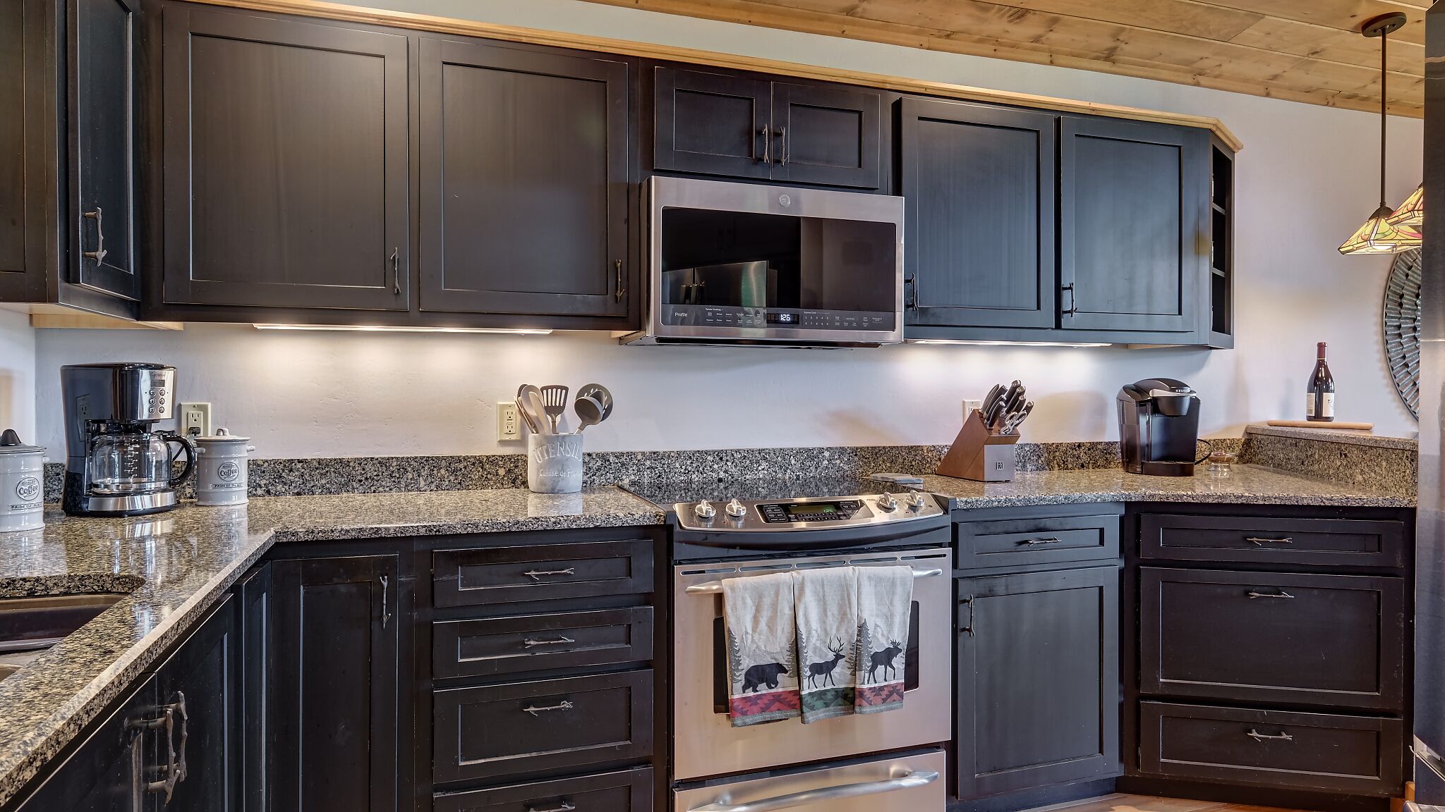 A kitchen with dark cabinets, a stainless steel range, and a coffee maker.