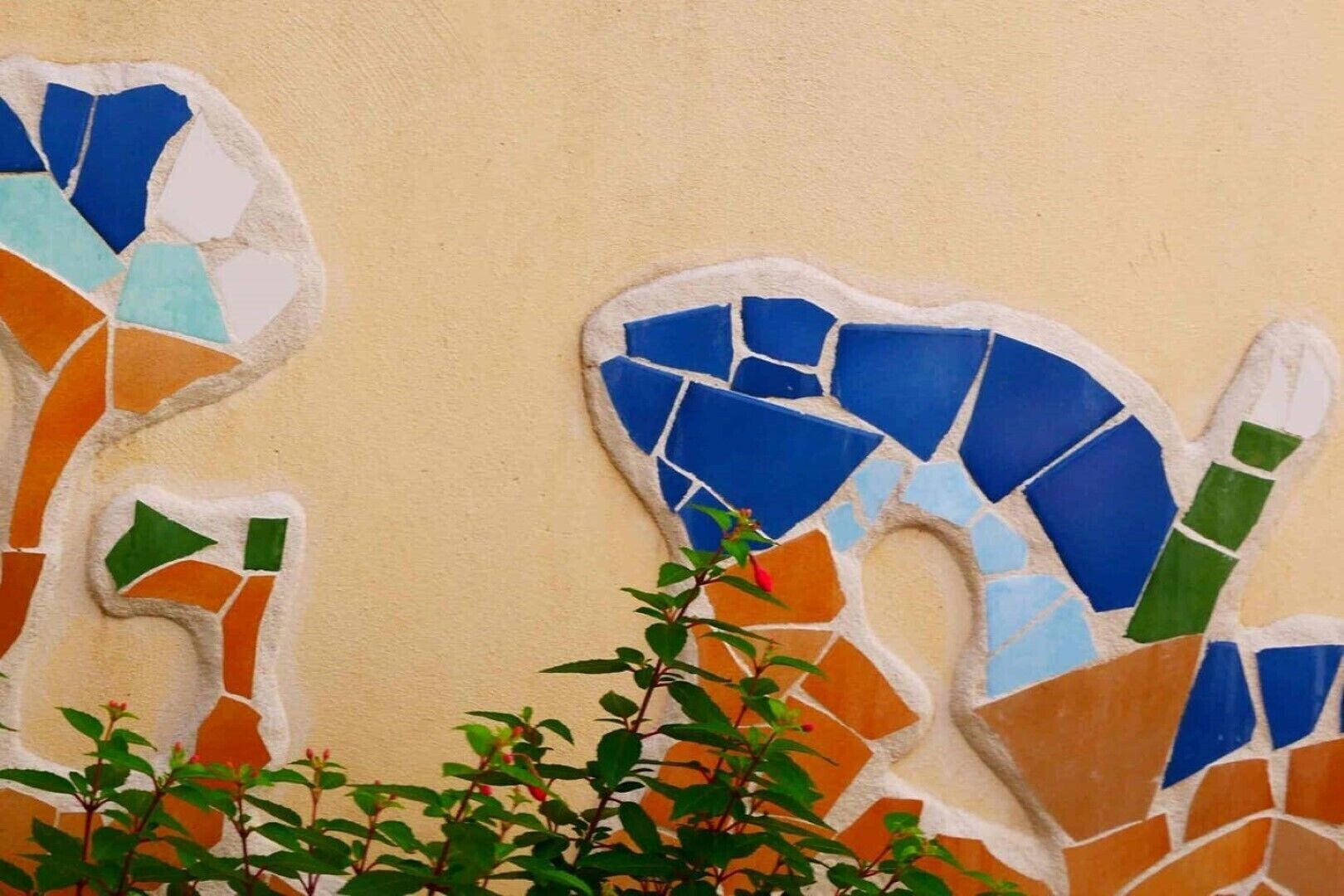 Pared con arte de mosaico que incluye baldosas azules, verdes y anaranjadas.