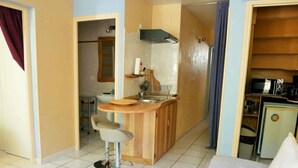 Een compacte hotelkamer met kitchenette, een bed en een klein zithoekje.