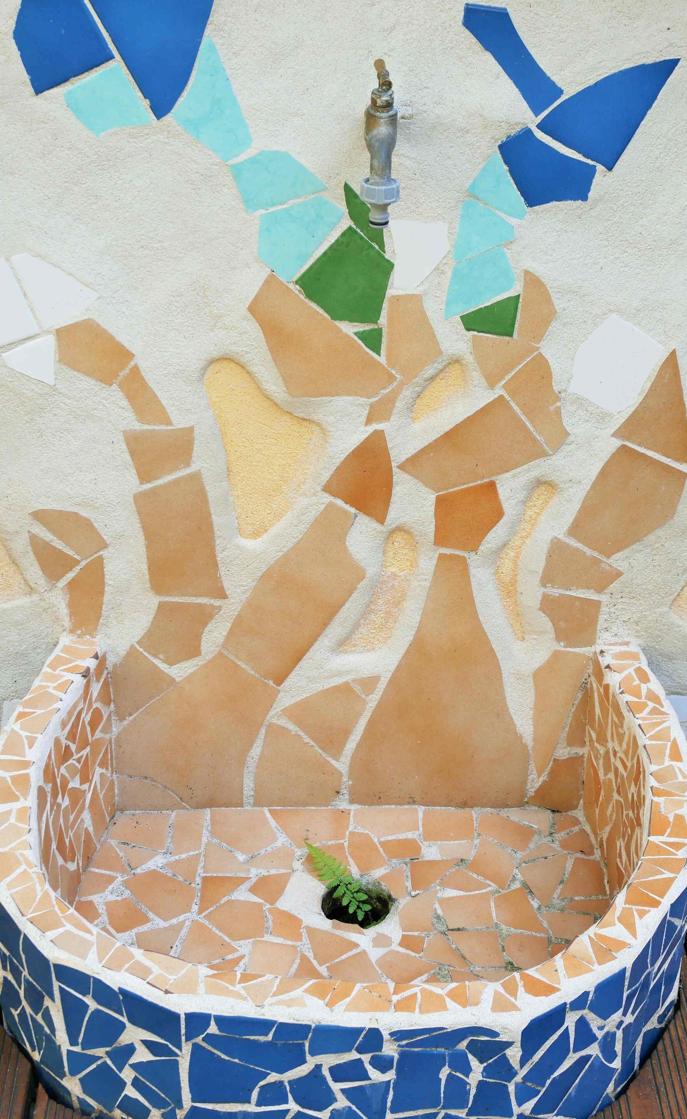 Una font de mosaic amb un sortidor central, envoltada per una balsa circular.