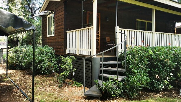 A wooden house with a porch, steps, and a covered area.