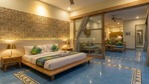 Un dormitorio con una cama grande, una mesita de noche, una lámpara, una pared con diseños intrincados y un ventanal corredero que da a un comedor.