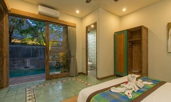 Quarto de hotel com porta de correr de vidro para uma piscina, guarda-roupa de madeira e cama com toalhas.