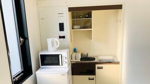 A compact kitchen with a microwave, refrigerator, sink, and a trash bin. - WELLSTAY　Osaka　Honmachi　Apartment hotel (Osaka)