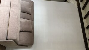 Een kamer met een grote, lichtkleurige bank en een witte muur.