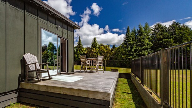 Une terrasse dotée de meubles en bois et d’une porte vitrée donnant sur un patio abrité.