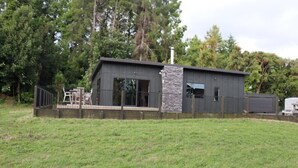 Un bâtiment moderne à deux étages, doté d’un mur d’accent en pierre, de grandes fenêtres et d’un espace extérieur clôturé.