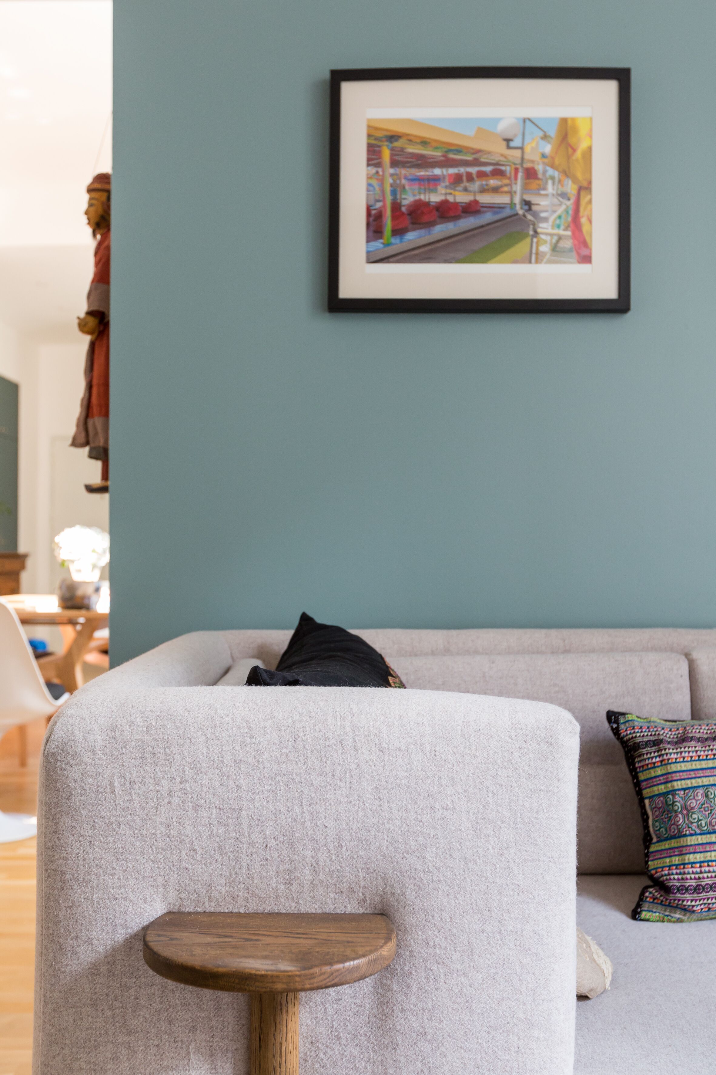 A living room with a grey sofa, a small wooden table, and a framed picture on the wall.