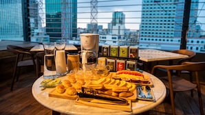 Una mesa con pasteles, té y café en un restaurante con vistas a la ciudad.