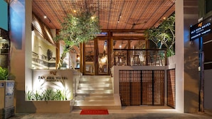 La entrada del Hotel Sky Gem, con techo de celosía de madera, una escalera y una alfombra roja.